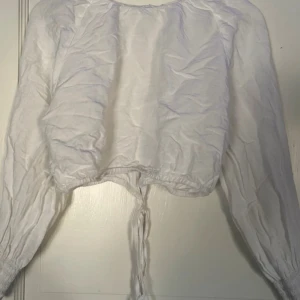 Vit knyt-blus - få gånger använd, bra skick. är skrynklig på bilden, men den har bara varit vikt. Är osäker på om storleken är XS eller S, skulle gissa på XS.  Katt o hund finns i hemmet.