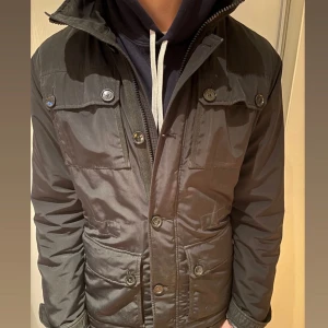 Svart fieldjacket J.Lindberg stl L/M - Svart fieldjacket från J.Lindberg i stl L men passar även M. Inga defekter. Nypris 4000 mitt pris 1099! Vid minsta lilla fundering hör av dig!