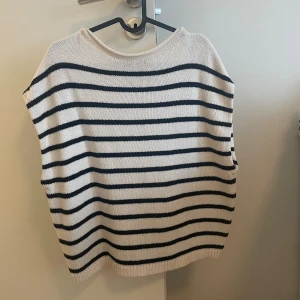 Randig stickad väst i vitt och svart - Säljer en snygg stickad väst med vita och svarta horisontella ränder. 