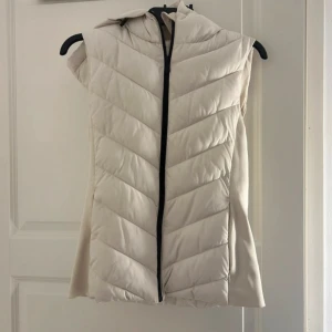 Figursydd Zara Väst - Västen är endast använd en gång. Köpte den för något år sedan. Är osäker men tror inte den finns kvar i Zaras sortiment längre. Västen är figursydd vilket gör att den verkligen sitter jätte snyggt. Den har även en luva.
