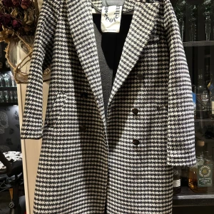 Rutig kappa från Scotch & Soda - Snygg lång kappa från Scotch & Soda i svartvitt rutigt mönster. Klassisk dubbelknäppning framtill, bred krage och raka ärmar. Tillverkad i ullblandning som håller dig varm och stilsäker under kyliga dagar.