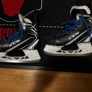 Svarta CCM Tacks skridskor med blå snören - Säljer ett par svarta CCM Tacks skridskor. Köpte nya vaxade snören till dem bara några veckor innan jag lade dessa på hyllan. En bra skridsko för nybörjaren eller för den som bara vill ha en bra skridsko för pengarna. 