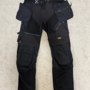 Arbetsbyxor Snickers Workwear 6902 - Hej!  Säljer ett par Snickers Workwear 6902 arbetsbyxor i mycket bra skick. De har endast använts en gång, så de är i princip som nya.  Riktigt bekväma och slitstarka byxor med stretchmaterial, bra passform och många praktiska fickor.  Nypris runt 1800-1900 kr, mitt pris: 1200 kr.  Kan skickas eller hämtas efter överenskommelse.  Säg bara till om du undrar något 😊