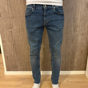 Tiger of Sweden – Slim Fit jeans i klassisk blå tvätt - Snygga jeans från Tiger of Sweden i en tidlös blå tvätt. Slim fit-modell med smal passform och bekväm stretch. Perfekta till både vardag och fest. ✔️ Storlek: 30/32 ✔️ Modell: Slim Fit ✔️ Färg: Blå ✔️ Skick: Mycket bra – inga hål eller fläckar 