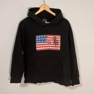 Ralph Lauren Svart USA Hoodie  - Säljer denna feta och eftertraktade hoodie från Ralph Lauren i storlek L (14-16). Jag skulle säga att den passar fint som en XS. Tröjan är i bra skick. Hör gärna av er vid funderingar 🙌🏻