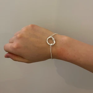 Silverarmband från wos (modell ofelia) - Stilrent armband i silver från WOS med en tunn kedja och en cool, organisk formad ring i mitten. Helt oanvänd och bypris är 399, har tyvärr slängt bort förpackningen