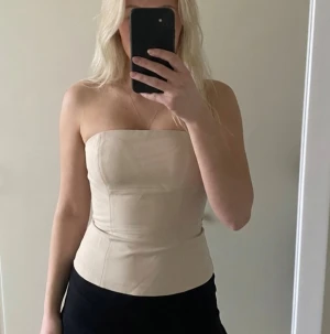 créme vit tubtopp  NAKD - Säljer en stilren cremevit tubtopp från NAKD i storlek 36.  Knappt använd skicket är mycket bra. Den har dragkedja och fäste på sidan och ett gummiband så att toppen inte åker ner