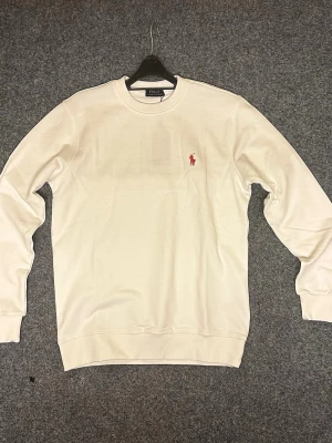 Crewneck från Polo Ralph Lauren, flera färger! - Stilrena crewnecks från Polo Ralph Lauren, finns I vit, svart och i mörkgrön. Tröjan har rund hals, långa ärmar och den klassiska röda Polo-loggan broderad på bröstet. Tillverkade i mjuk bomull för en skön och avslappnad look.