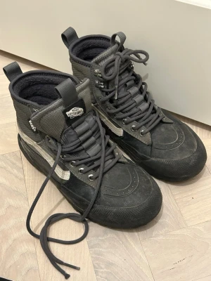 Vans Gore-Tex All-Weather boots Sk8-hi 35 - Säljer ett par svarta och grå Vans Gore-Tex All-Weather boots Sk8-hi Mte med grov sula och snörning. Skorna har vit sidostripes, röda detaljer på hälen och är tillverkade i slitstarkt syntetmaterial med vattentätt Gore-Tex-foder. Jättevarma och perfekt till vinter med extra grepp under sulan. Använda en vinter säsong, men bra skick. Nypris 2400 sek, slutsålda och svåra att få tag på. 