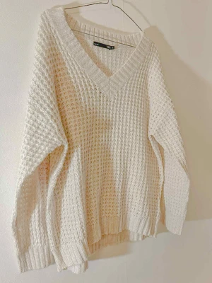 Vit stickad tröja med v-ringning - Säljer en vit stickad tröja från lager157, storlek S. Tröjan har en bred v-ringad hals och ett grovt, ribbat mönster som ger en mysig känsla. Långärmad och loose passform, perfekt för lager-på-lager. Ribbstickade muddar vid ärmslut och nederkant.
