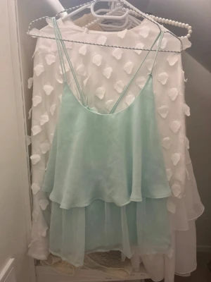 Ljusblå linnetopp med dubbla lager - Säljer en ljusblå linnetopp från H&M med tunna axelband som korsas i ryggen. Toppen har dubbla lager i ett skirt, lätt material som ger en flowy känsla. Perfekt för varma dagar och enkel att styla med jeans eller kjol. Vet inte vilket märke den är ifrån, köpte den på vinted och har aldrig haft på mig den.