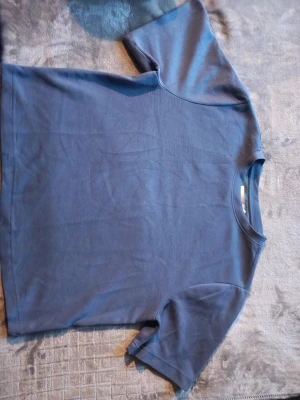 Blå basic t-shirt från  Lager 157 - En enkel blå t-shirt från Lager 157 i storlek XS. T-shirten har rund halsringning och korta ärmar. Tillverkad i mjuk bomull, perfekt för en chill och avslappnad stil.