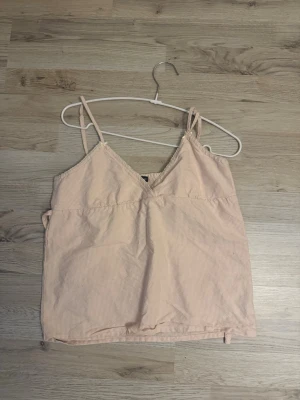 Ljusrosa ribbad linnetopp brandy Melville  - Säljer en ljusrosa linnetopp med smala axelband och v-ringad hals. Toppen har en ribbad struktur och är ärmlös, perfekt för varma dagar. Enkel och stilren design som funkar till många olika looks. Det är one size fits all.