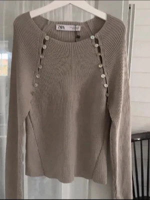 Beige topp med knappar från zara  - Säljer en beige ribbad croppad topp från Zara med långa ärmar och knappar. Knappt använd!