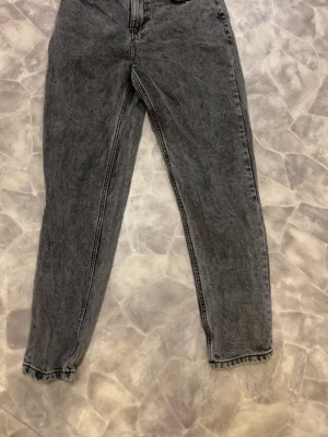Grå loose jeans från Grunt, storlek 26 - Säljer ett par mörkgrå loose fit jeans från Grunt i storlek 26 som motsvarar storlek 158/164. Modellen heter GRStreet Loose Dark Grey och har en relaxed passform med raka ben och klassisk femficksdesign. Jeansen är tillverkade i bomull och har en snygg tvättad look.
