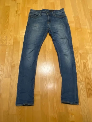 Blå jeans från Tiger of Sweden - Säljer nu dessa blå jeans från Tiger of Sweden då de inte kommer till användning. Modellen är pistolero och skicket skulle jag säga är 7/10 inga defekter förutom ett litet hål ovanför bakfickan. Hör av dig vid funderingar!
