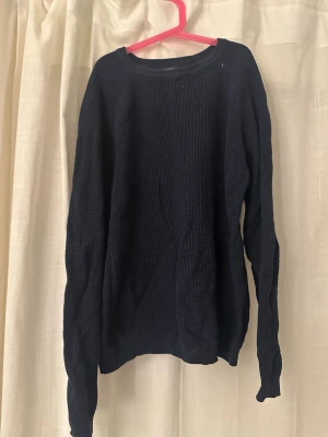 Mörkblå stickad tröja Dressmann M - Säljer en mörkblå stickad tröja från Dressmann i storlek M. Tröjan har rund hals och är ribbstickad med långa ärmar. Perfekt för kyliga dagar och enkel att matcha med jeans eller chinos.