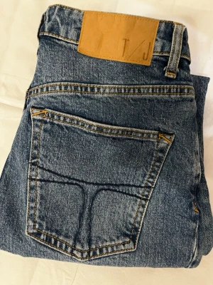 Blå jeans från True of Sweden, Meg - Snygga blå jeans från True of Sweden i modellen Meg. Klassisk femficksdesign med raka ben och hög midja. Jeansen har en ljusblå tvätt och detaljerade sömmar med brunt läderpatch bak i midjan. Perfekt passform för dig som gillar stilrena jeans.