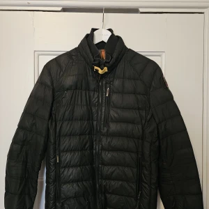 Svart pufferjacka från Parajumpers - Säljer en svart pufferjacka från Parajumpers med hög krage och gul detalj vid halsen. Jackan har flera dragkedjeförsedda fickor och quiltad design. Perfekt för kalla dagar och har en riktigt snygg streetstil. Defekter finns tyvärr då den användes dagligen för några år sedan