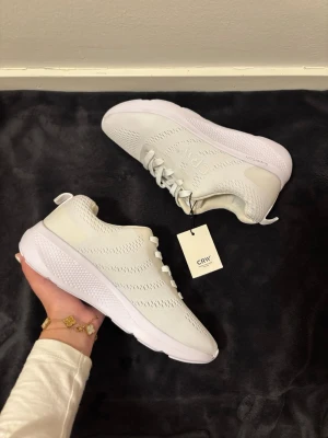 CRW Vita Sneakers 39 - Helt oanvända vita sneakers från CRW i storlek 39, prislappen sitter kvar. Skorna är lätta och sköna, perfekta både för löpning och vardag. Mjuk sula med bra komfort och stilren design som är lätt att matcha. Kartong medföljer tyvärr ej💕