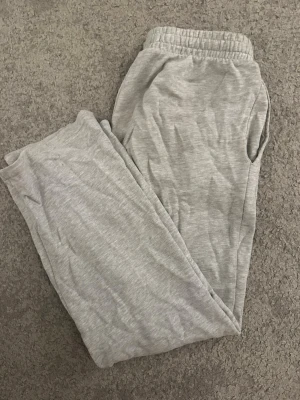 Grå mjukisbyxor med resårmidja - Säljer ett par grå mjukisbyxor med resår i midjan och sidofickor. Perfekta för chill dagar hemma eller när du vill vara extra bekväm. Materialet är mjukt och stretchigt, vilket gör dem riktigt sköna att ha på sig.