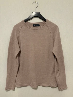 Beige stickad tröja från Riley - Snygg beige stickad tröja från Riley med rund hals och långärmad design. Tröjan har en slim passform och är tillverkad i mjukt material som känns skönt mot huden. Perfekt att bära under hösten och vintern för en stilren look.