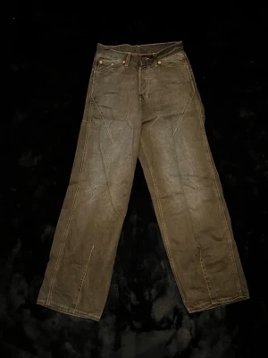 Y2K jeans - Säljer ett par bruna jeans med unika diagonala sömmar framtill. Byxorna har klassiska fickor och en enkel bakficka med läderpatch. Ordinarie pris 1200 pågrund av limited edition
