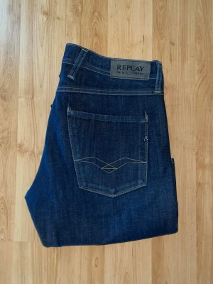 Replay Hyperflex Anbass jeans - Snygga Replay Hyperflex Anbass jeans i mörkblå färg med raka ben. Obs Längdmåttet saknas men jag uppskattar storleken till L34, men utgå från måtten. Midja 41cm, längd 114cm. OBS jeansen har ett litet hål upptill - se bilder. JAG SKICKAR EJ FLER BILDER NÄR JAG BÄR JEANSEN! för bättre inblick i passformen rekommenderar jag att googla på modellnamnet. För storleksguide kolla måtten noggrant då jeansen alltid kan vara uppsydda heller krympta och jag tar ej emot returer :) s5,2