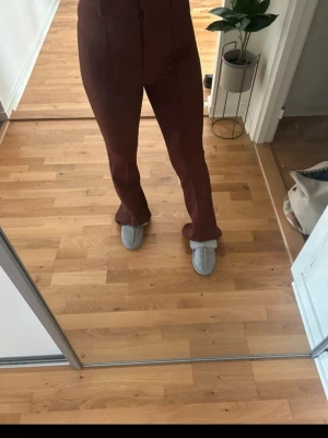 Bruna bootcut byxor med hög midja - Säljer ett par bruna bootcut byxor med hög midja. Byxorna har en snygg, figurnära passform upptill och vida ben nedtill. Materialet känns mjukt och har en lätt stretch, perfekt för dig som gillar retrovibbar och vill sticka ut lite extra.