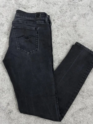 Replay Luz svarta jeans - Svarta Replay Luz jeans med klassisk femficksdesign och snygga detaljer på bakfickorna. Jeansen har smal passform och är tillverkade i stretchigt jeansmaterial för extra komfort. Perfekt för dig som gillar en stilren och modern look.