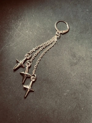 By prisförslag- 1 st Silvrig öronhänge med stjärnor - ett snyggt öronhänge i silverfärgad metall med tre kedjor och hängande stjärnberlocker. Perfekt accessoar för dig som gillar detaljer som sticker ut och ger en cool vibe till din stil.