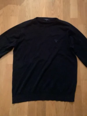 Mörkblå finstickad bommuölströja tröja från GANT - Mörkblå stickad tröja från GANT i storlek M. Klassisk rund halsringning och långärmad modell med diskret ljusblå logga på bröstet. Perfekt för dig som gillar stilrena och enkla plagg. Materialet är mjukt och bekvämt, passar till många olika outfits. Hör av er vi frågor eller funderingar! Den är lite liten i storleken.