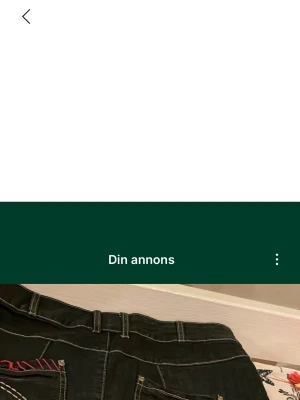 Svart jeanskjol med broderier - Cool svart jeanskjol med kontrastsömmar och broderade detaljer i rött, vitt och rosa. Kjolen har fickor både fram och bak, bälteshällor och unika broderade blommor och hexagoner framtill. Snygga dekorsömmar och färgglada detaljer ger kjolen en personlig touch. Säljs på fler sidor. Köparen betalar frakt.