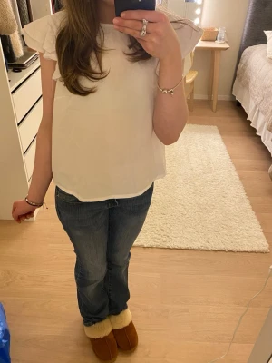 Vit blus från Lindex med volangärmar - Säljer denna superfina vita blusen från Lindex med volanger vid ärmarna. Helt oanvänd!