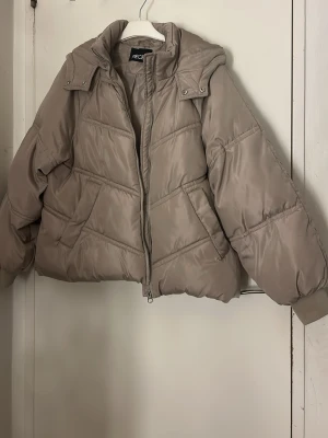 Beige pufferjacka  - Säljer en beige pufferjacka med huva och dragkedja framtill. Jackan har en loose passform, quiltade detaljer och två fickor på sidorna. Perfekt för kalla dagar och har en snygg, enkel look som funkar till många stilar.  Pris kan diskuteras, tvätt ingår innan leverans ❤️