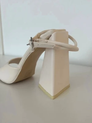 Sandaler med trekantig klack - Säljer ett par sandaler med trekantig klack och öppen fyrkantig tå. Justerbar ankelrem. Oanvända, endast provade ett par gånger. Mindre skavank på ena blockklacken, syns på första bilden. 