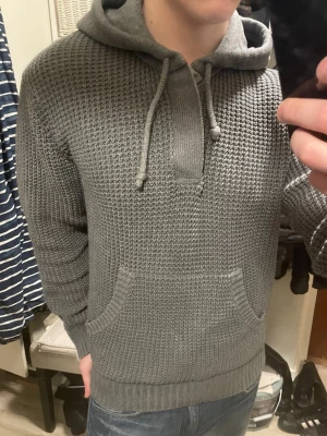 Grå stickad hoodie - Otroligt fet, varm och unik grå stickad hoodie med knappar vid halsen. Modellen är 180cm, 75kg. Storlek L men skulle säga att den passar mer som M. Priset kan såklart diskuteras.