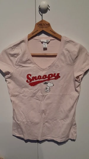 Rosa topp - En rosa topp med knallrosa text och Snoopy tryck.