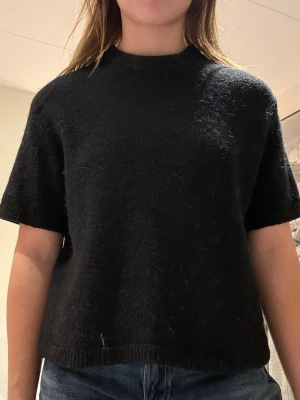 Svart stickad kortärmad tröja - Mysig svart stickad tröja med trekvartsärmar. Fint skick och säljer då den är för liten. Fint skick. Storlek S men sitter som XS