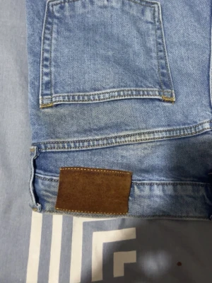 Blå raka jeans från Jack & Jones - Snygga ljusblå jeans från Jack & Jones med klassisk femficksdesign och raka ben. Jeansen har normal passform och är tillverkade i slitstarkt bomullsmaterial. Perfekt för dig som gillar en enkel och clean look med lite retrovibe.