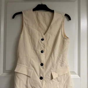 Ärmlös beige kostym med byxa - Snygg tvådelad kostym i beige med ärmlös kavaj och matchande byxor som är lite utsvängda ner till 