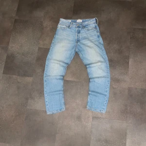 Jack & Jones Loose/Chris ljusblå jeans - Ljusblå jeans från Jack & Jones i modellen Loose/Chris. Jeansen har en loose passform med raka ben och klassisk femficksdesign. Perfekta för dig som gillar en bekväm och trendig stil.