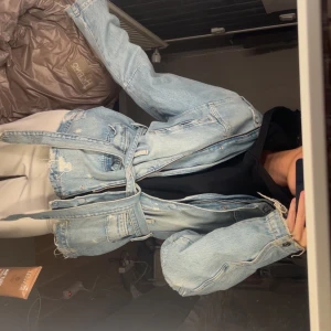 Ljusblå jeansjacka med bälte - Säljer skit snygg en oversized ljusblå jeansjacka med bälte i midjan och slitna detaljer. Jackan har dragkedja, knappar och flera fickor framtill. Säljer jacka pga att det inte var riktigt min stil och den är använd enstaka gång.💓
