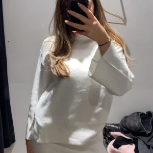 Vit oversized stickad tröja - Säljer en vit oversized stickad tröja med lång ärm och avslappnad passform. Tröjan har en enkel design med rund halsringning och mjukt material som känns skönt mot huden. Perfekt att slänga på sig när det är kyligt ute. Aldrig använd