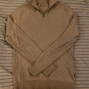 Beige stickad half zip från Jack & Jones - Snygg beige stickad tröja från Jack & Jones med half zip och hög krage. Tröjan har långärmade ribbade muddar och ribbad nederkant. Perfekt för dig som gillar stilren och enkel design med en chill vibe.