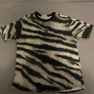 Zebramönstrad t-shirt från Stone Island - Säljer en riktigt fet zebramönstrad t-shirt från Stone Island. T-shirten har svartvitt mönster, rund hals med svart kant och en liten broderad logga på bröstet. 