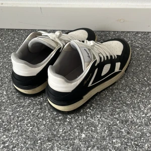 Axel Arigato skor - Snygga sneakers från Axel Arigato i strl 43. Skorna har snörning, perforerade detaljer på tån och sidan samt en beige sula för en retrovibe. Tillverkade i skinn och textil för en clean och sportig look.                                                      Nypris: 3450kr