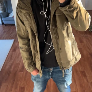 Olivgrön parkajacka från Hollister XS - Snygg olivgrön parkajacka från Hollister i storlek XS. Jackan har huva, flera fickor med lock och dragkedja framtill. Perfekt för dig som vill ha en stilren och praktisk jacka med streetkänsla. Jag är ≈175 och passar mig men passar dig som är upp till 180. Kostar 1000kr ny