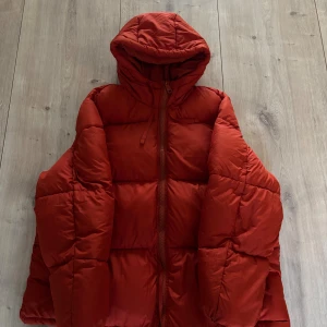 Röd pufferjacka från H&M med huva - Säljer en röd pufferjacka från H&M i storlek M. Jackan har en oversized look, huva och dragkedja framtill. Perfekt för kalla dagar och ger en cool vibe till din outfit. Materialet är syntet och jackan är quiltad för extra värme. Har några skavanker (se bild) men annars i väldigt bra skick. Ord pris 499kr