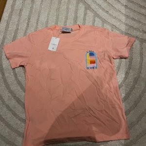 Casa Blanca rosa t-shirt med tryck - Snygg rosa t-shirt från Casablanca med färgstarkt grafiskt tryck både fram och bak. T-shirten har rund hals och korta ärmar, tillverkad i mjuk bomull. Perfekt för dig som gillar unika prints och vill sticka ut med en cool vibe.